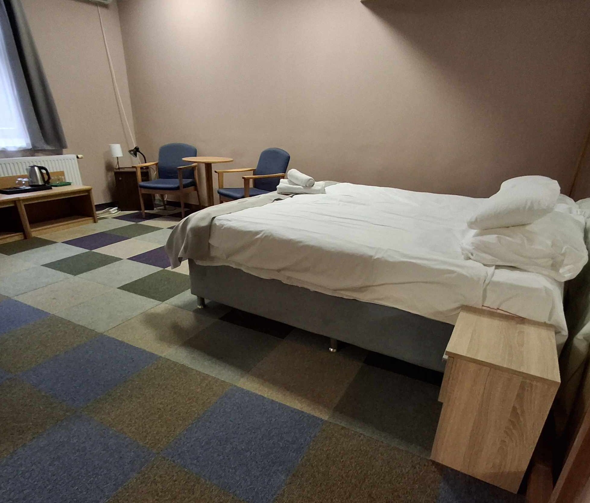 Una habitación de hotel con cama, escritorio, silla y una mesita.