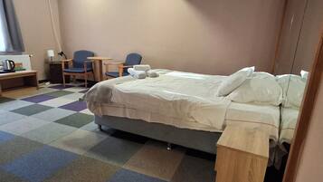 A hotel room with a bed, a desk, a chair, and a small table.