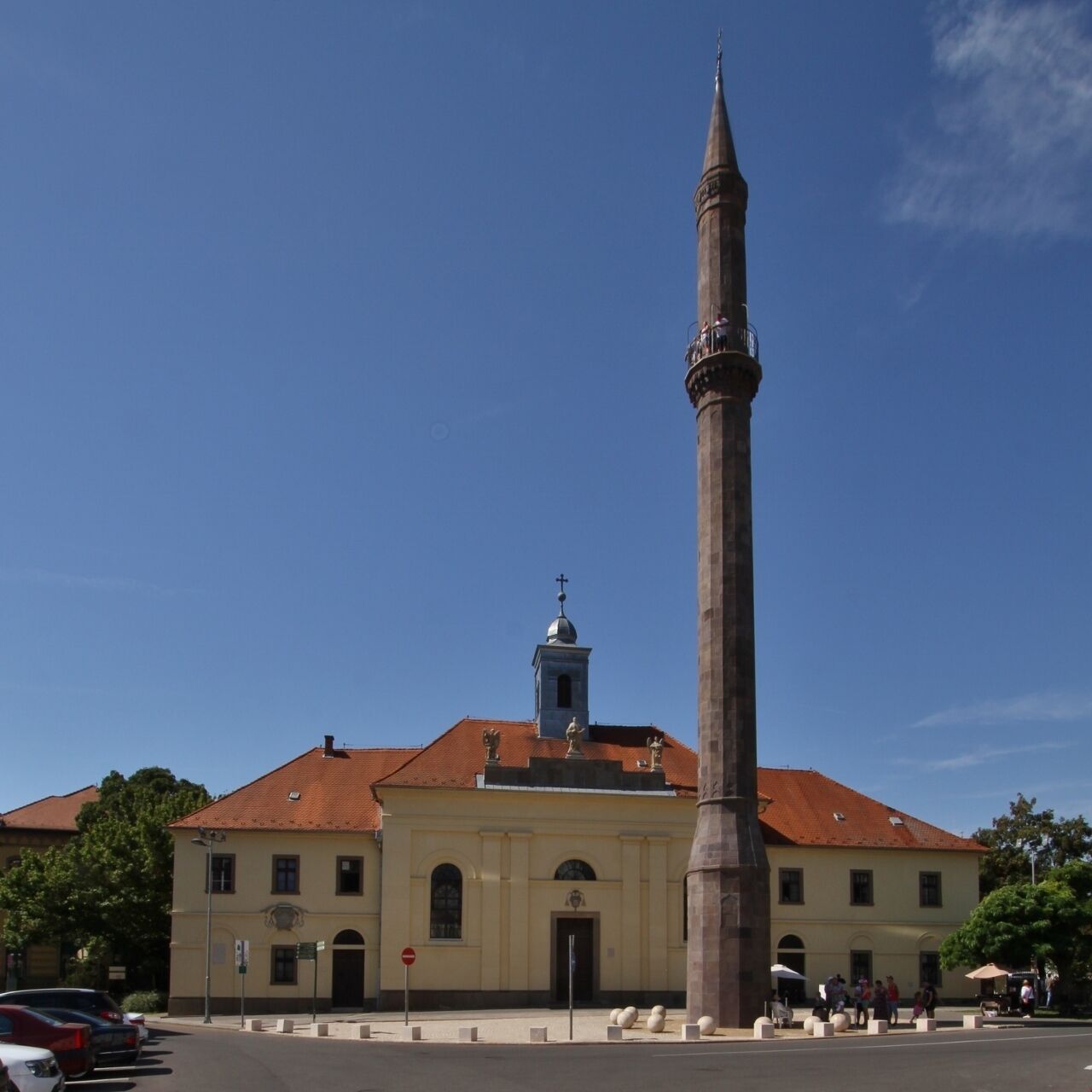 Una iglesia con un campanario alto y un gran obelisco al frente.