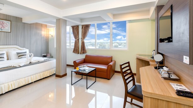 Una habitación de hotel con cama, sofá, escritorio y un ventanal con vistas.