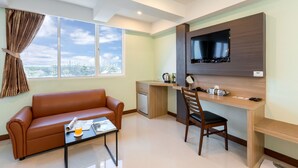 Una sala de estar moderna con un sofá, una mesa de centro, un escritorio y un televisor montado en la pared.