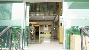 Un hall de hotel con mostrador de recepción, una estatua y una escalera que sube a un piso superior.