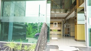Un vestíbulo de hotel con entrada de cristal, una escalera y un cartel que indica un restaurante.