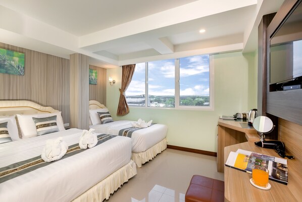 Habitación de hotel con dos camas, un escritorio con espejo, un televisor de pantalla plana y un ventanal con vista a la ciudad.