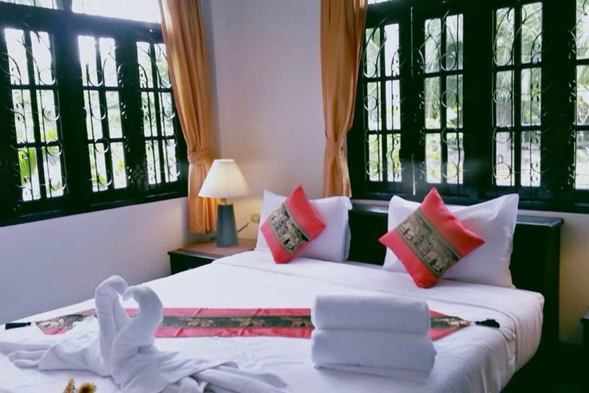 A hotel room with a bed, two nightstands, two lamps, and large windows with decorative grills.