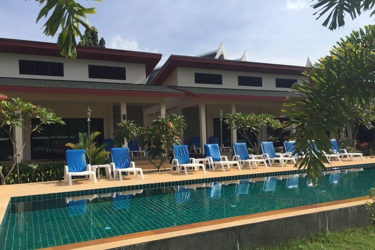 A swimming pool with lounge chairs and palm trees.