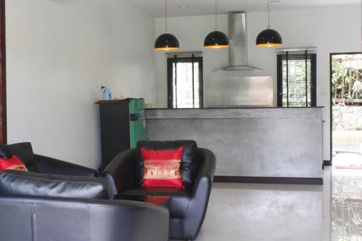 A modern living room with a sofa, a coffee table, and a red patterned wall.