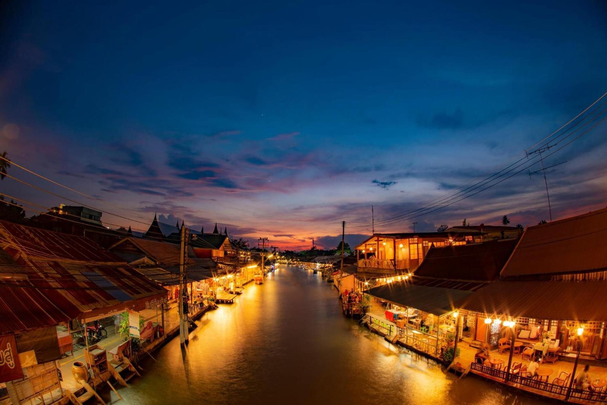 A riverside town with buildings along the water, featuring a bridge and boats.