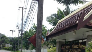 A sign for a bungalow with a palm tree and a white fence in the background. - Naya Pool Villa (Rawai)