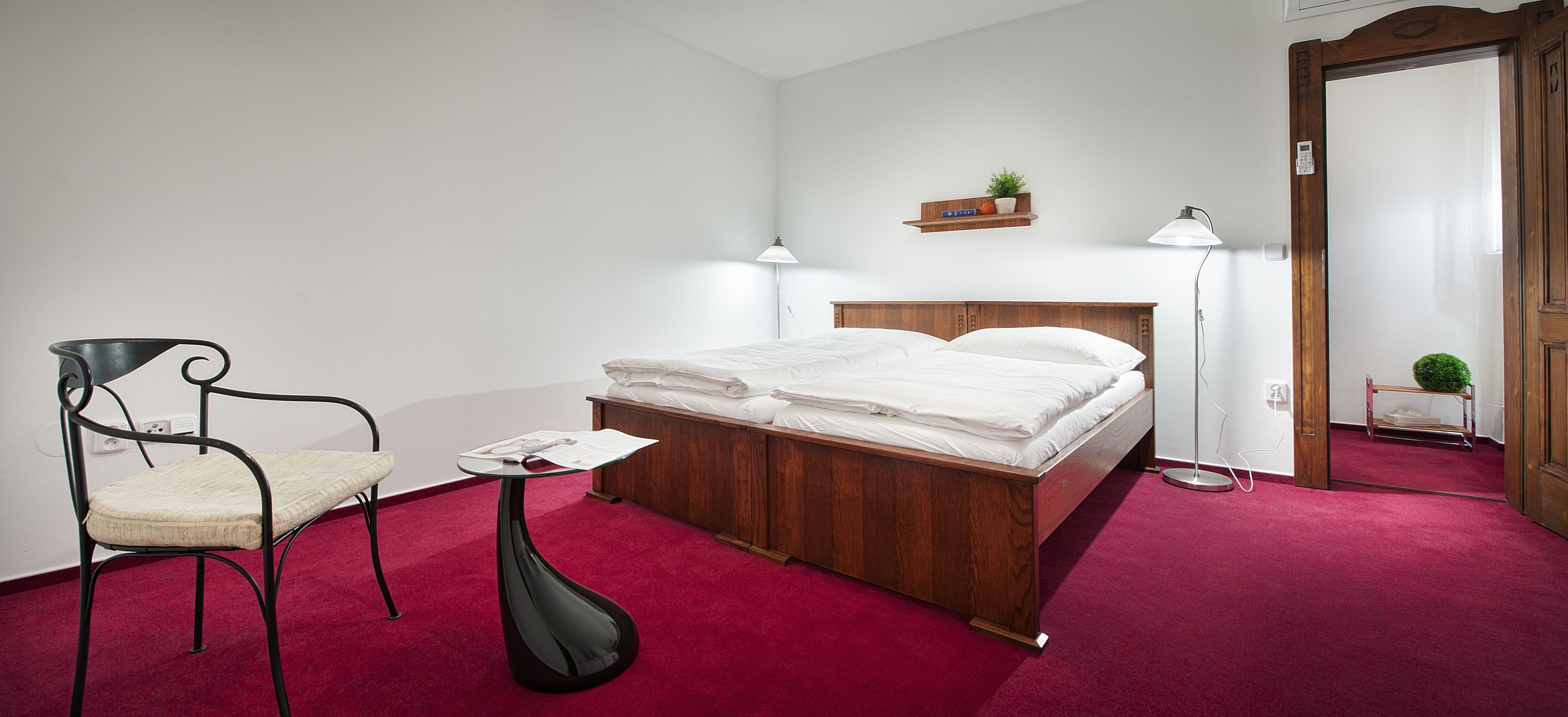 Une chambre à coucher avec un lit en bois, une chaise, une petite table et une lampe de chevet.
