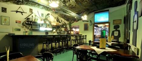 A bar area with stools and tables, a counter with 'STRELIVO' branding, and various decorations on the walls.