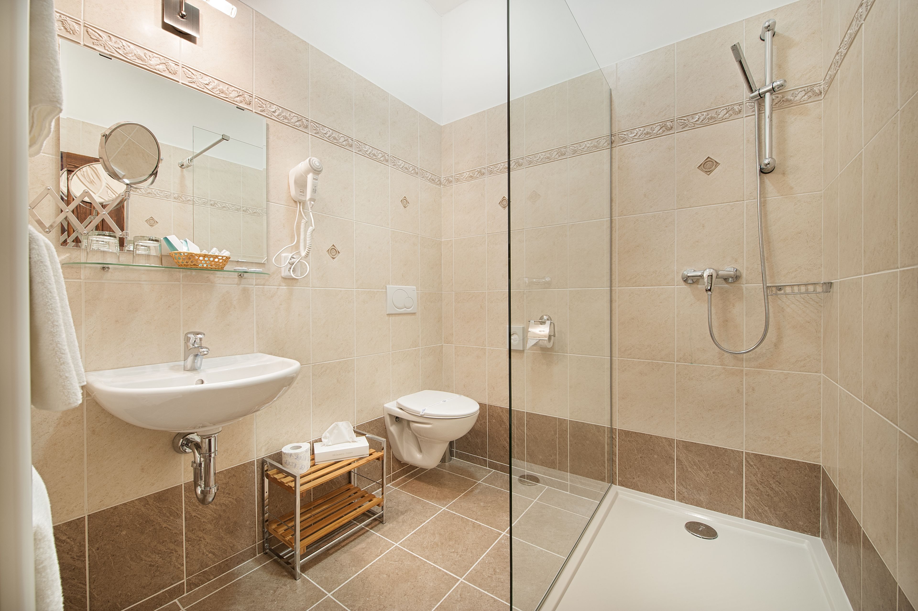 Un baño con lavabo, inodoro y ducha con mampara de vidrio.