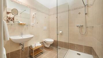Un baño con lavabo, inodoro y ducha con mampara de vidrio.
