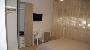 A bedroom with a bed, a desk, and a TV. - La Perla Affittacamere (La Spezia)