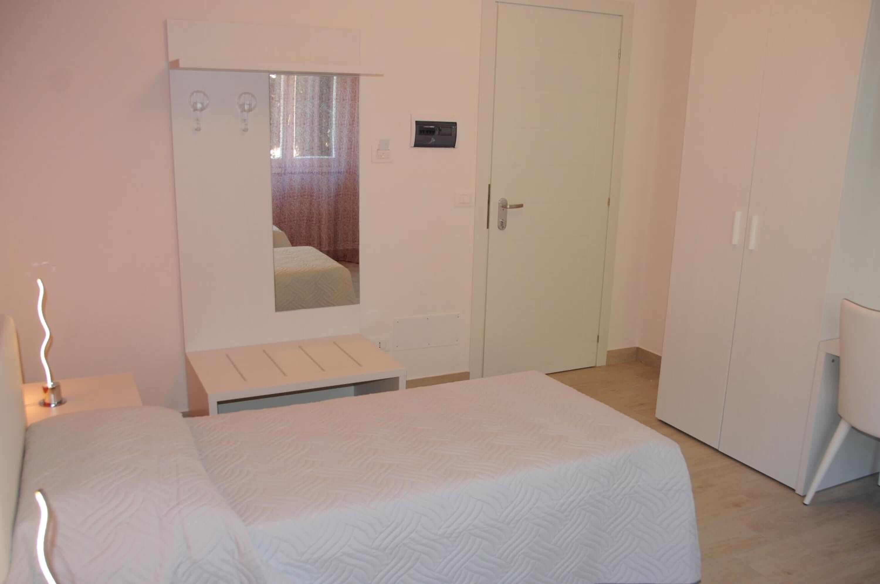 Ein Schlafzimmer mit Bett, Kleiderschrank, Spiegel und Nachttisch.