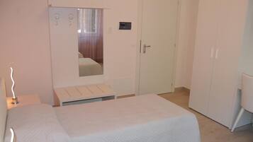 Ein Schlafzimmer mit Bett, Kleiderschrank, Spiegel und Nachttisch.