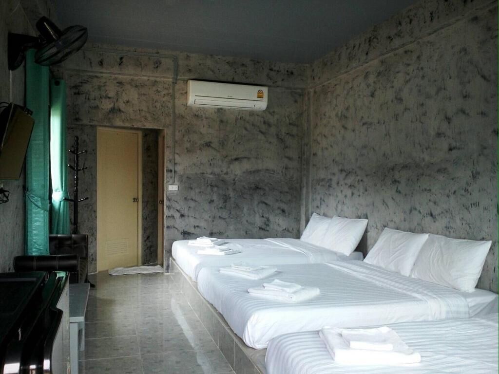 A hotel room with a bed, a desk, and an air conditioning unit.