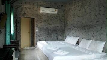 A hotel room with a bed, a desk, and an air conditioning unit.