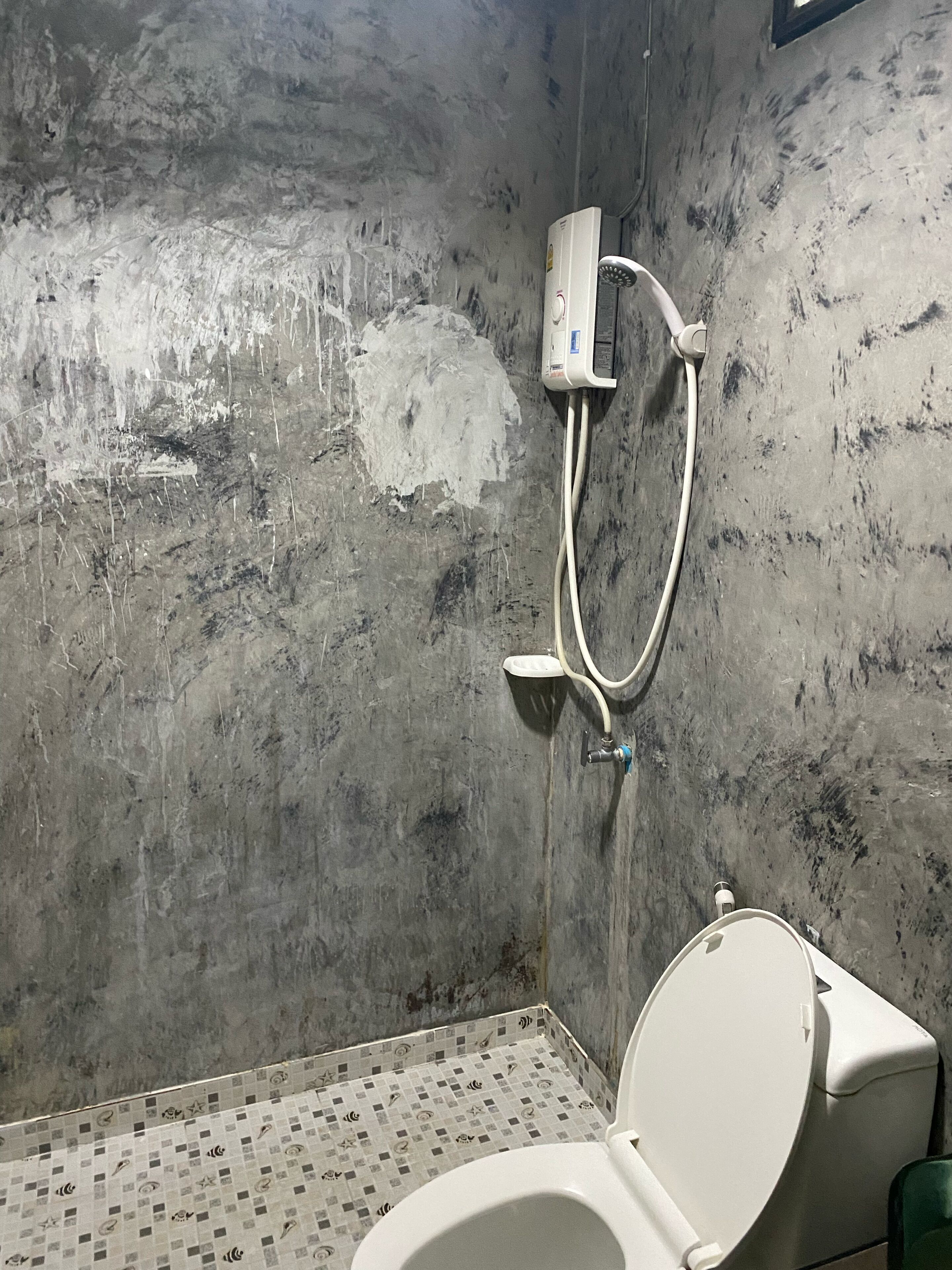 A bathroom with a toilet, a shower, and a tiled floor.