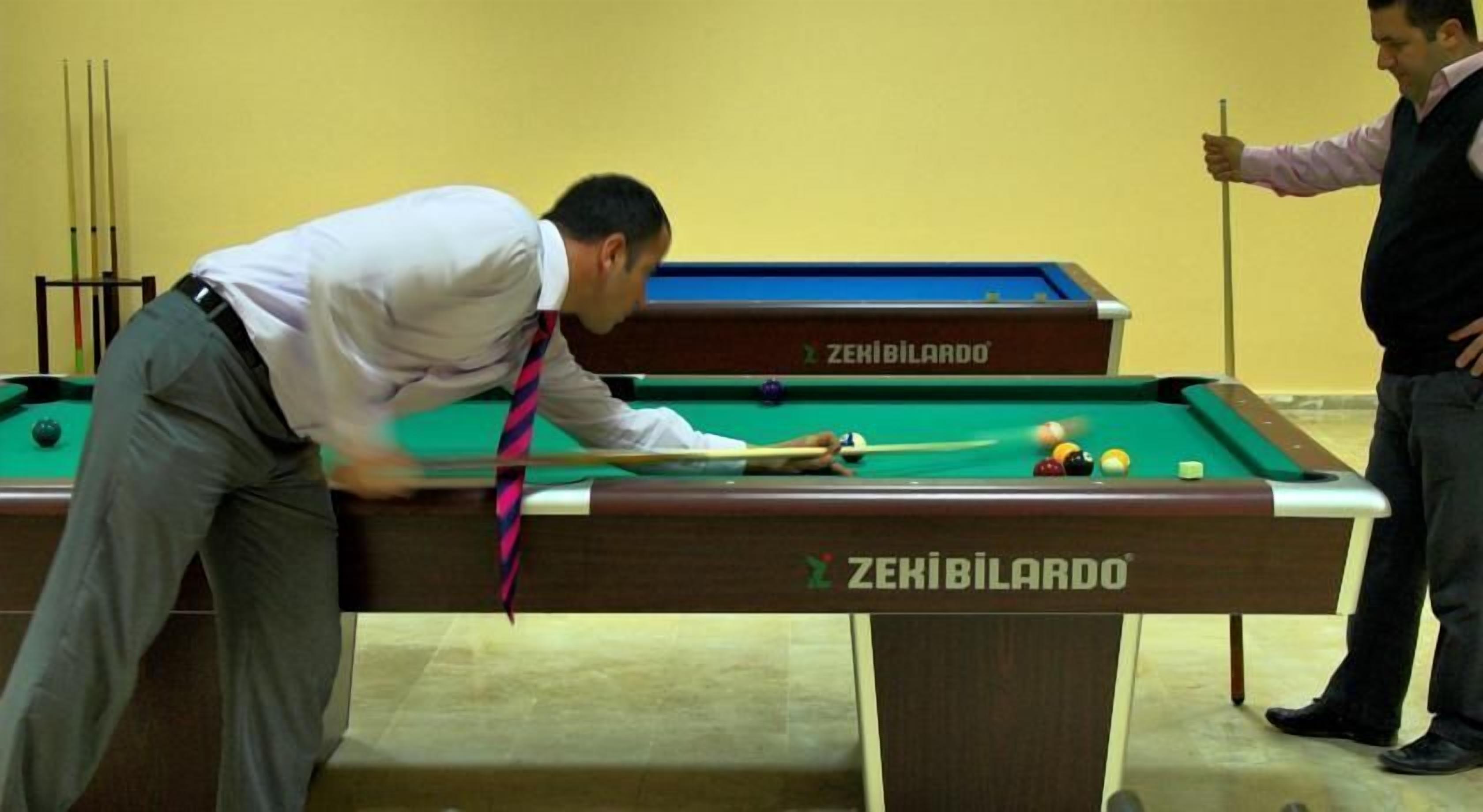 Una mesa de billar con superficie de fieltro verde y un mantel con el logo de la marca.