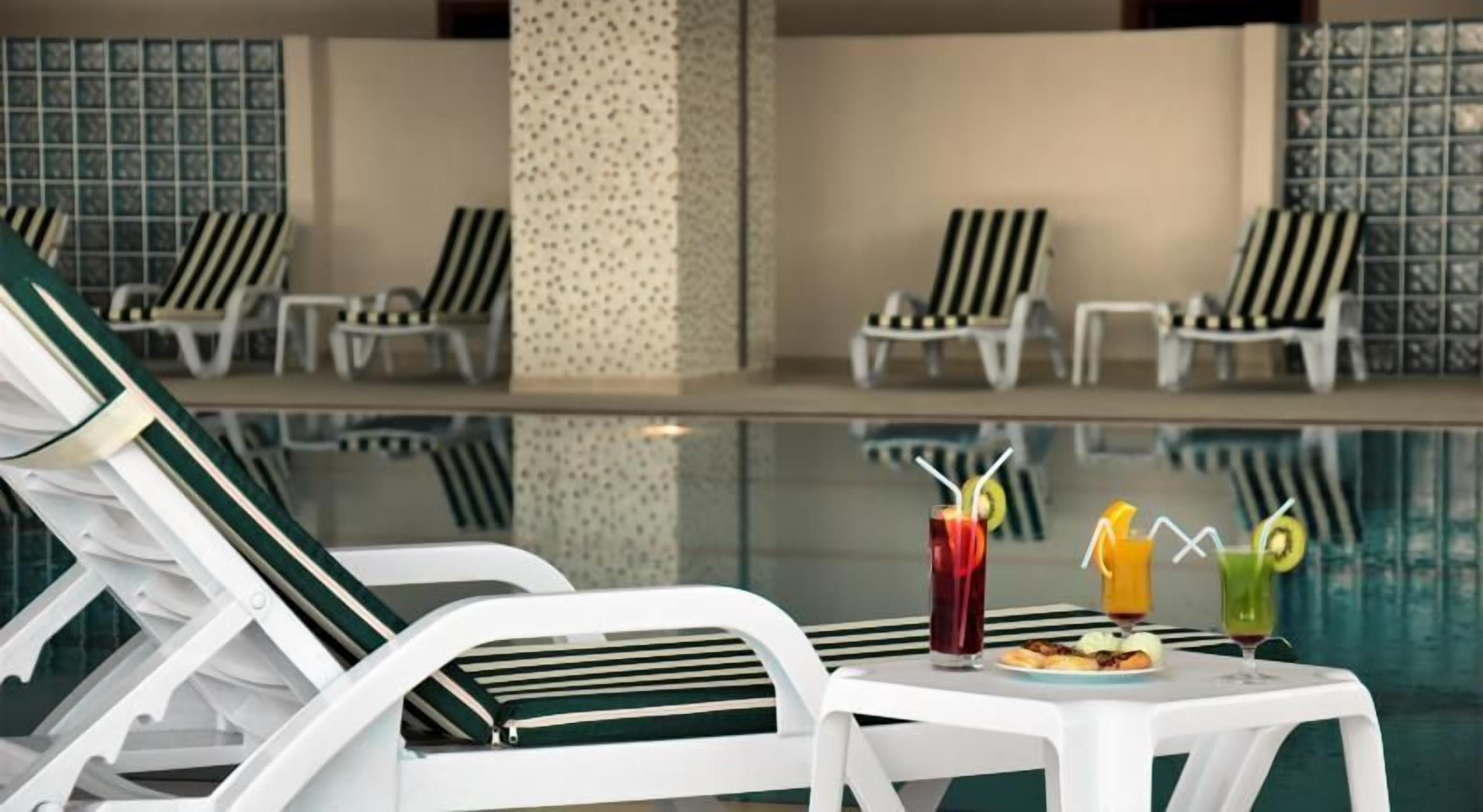 Alberca techada, alberca al aire libre y sombrillas en la alberca