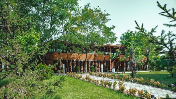 A building with a wooden exterior, surrounded by a well-maintained garden and a paved pathway. - Buyuk Anadolu Eregli Hotel (Karadeniz Eregli)