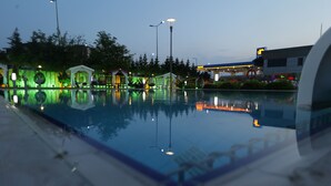 A swimming pool with a reflection of street lamps and a building with a yellow sign. - Buyuk Anadolu Eregli Hotel (Karadeniz Eregli)