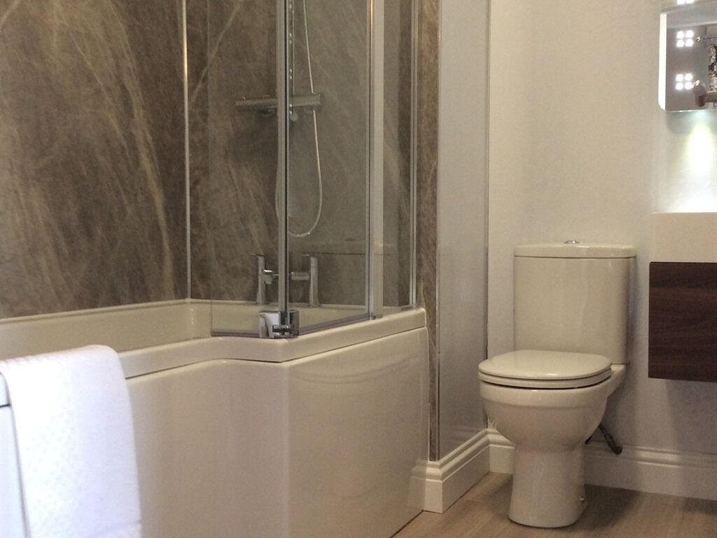Un baño con cabina de ducha de vidrio, un inodoro blanco y un perchero para toallas.