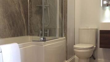 Un baño con cabina de ducha de vidrio, un inodoro blanco y un perchero para toallas.