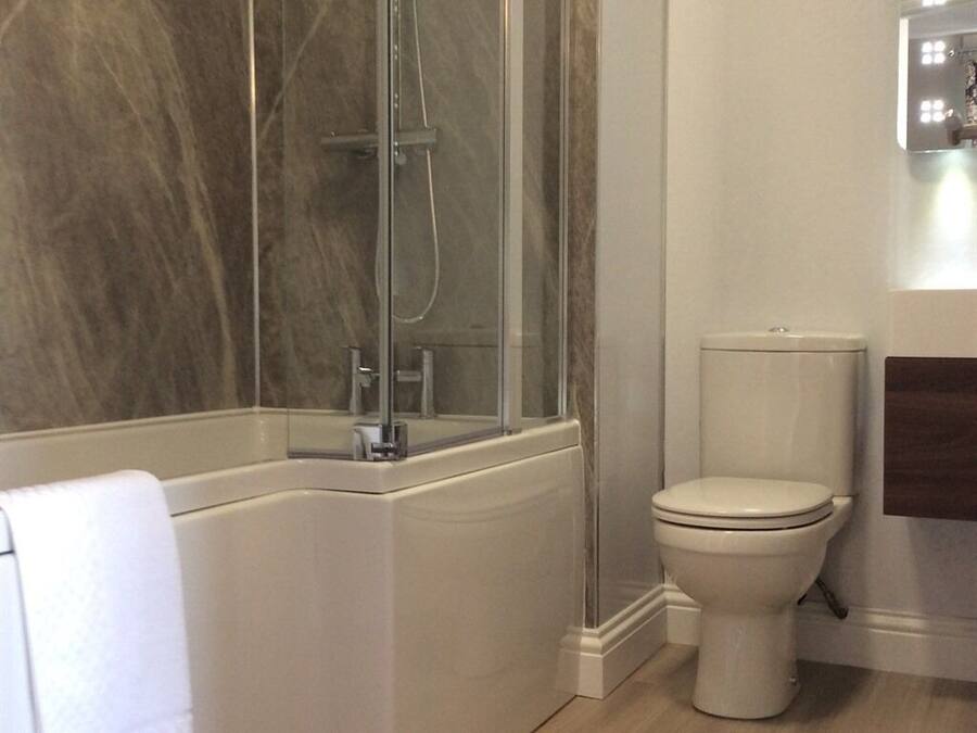 Un baño con cabina de ducha de vidrio, un inodoro blanco y un perchero para toallas.
