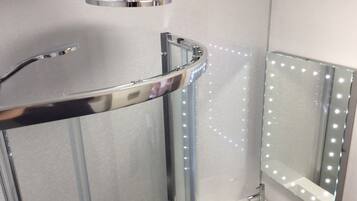 A modern bathroom with a curved shower enclosure, a vanity with a mirror, and LED lights along the shower wall.