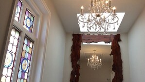 A room with a chandelier, stained glass windows, and a unique wooden mirror.