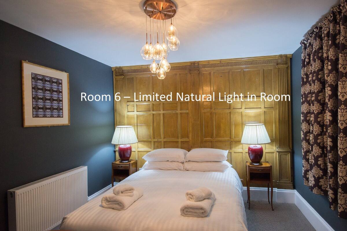 A hotel room with a large bed, two bedside tables with lamps, a ceiling light fixture, and a framed picture on the wall.