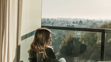 Una persona sentada en una silla junto a una ventana con vistas a un paisaje urbano.