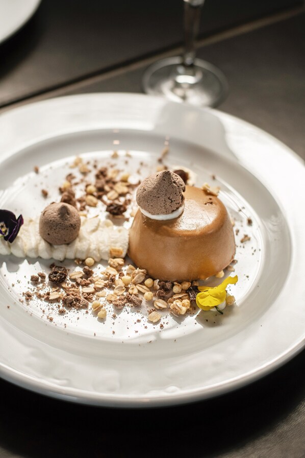 A dessert on a white plate with a glass of wine in the background.