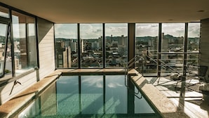 Una piscina interior moderna con ventanas amplias que ofrecen vistas a la ciudad.