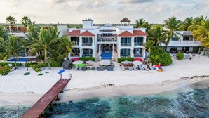 A beachfront property with a swimming pool, beach chairs, umbrellas, and a wooden dock leading to the water. - Cielo Maya Beach Tulum (Tulum)