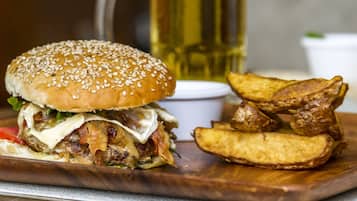 A burger with fries and a drink on a wooden board.