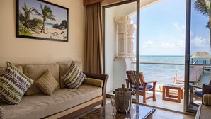 A room with a sofa, a coffee table, and a view of the ocean through large glass doors. - Cielo Maya Beach Tulum (Tulum)