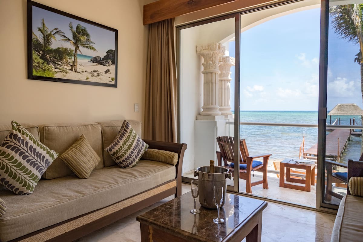 Ein Zimmer mit einer Couch, einem Couchtisch und Blick auf das Meer durch große Glasüren.