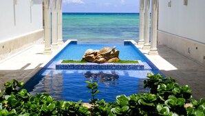 A pool with a view of the ocean, surrounded by white columns and greenery. - Cielo Maya Beach Tulum (Tulum)