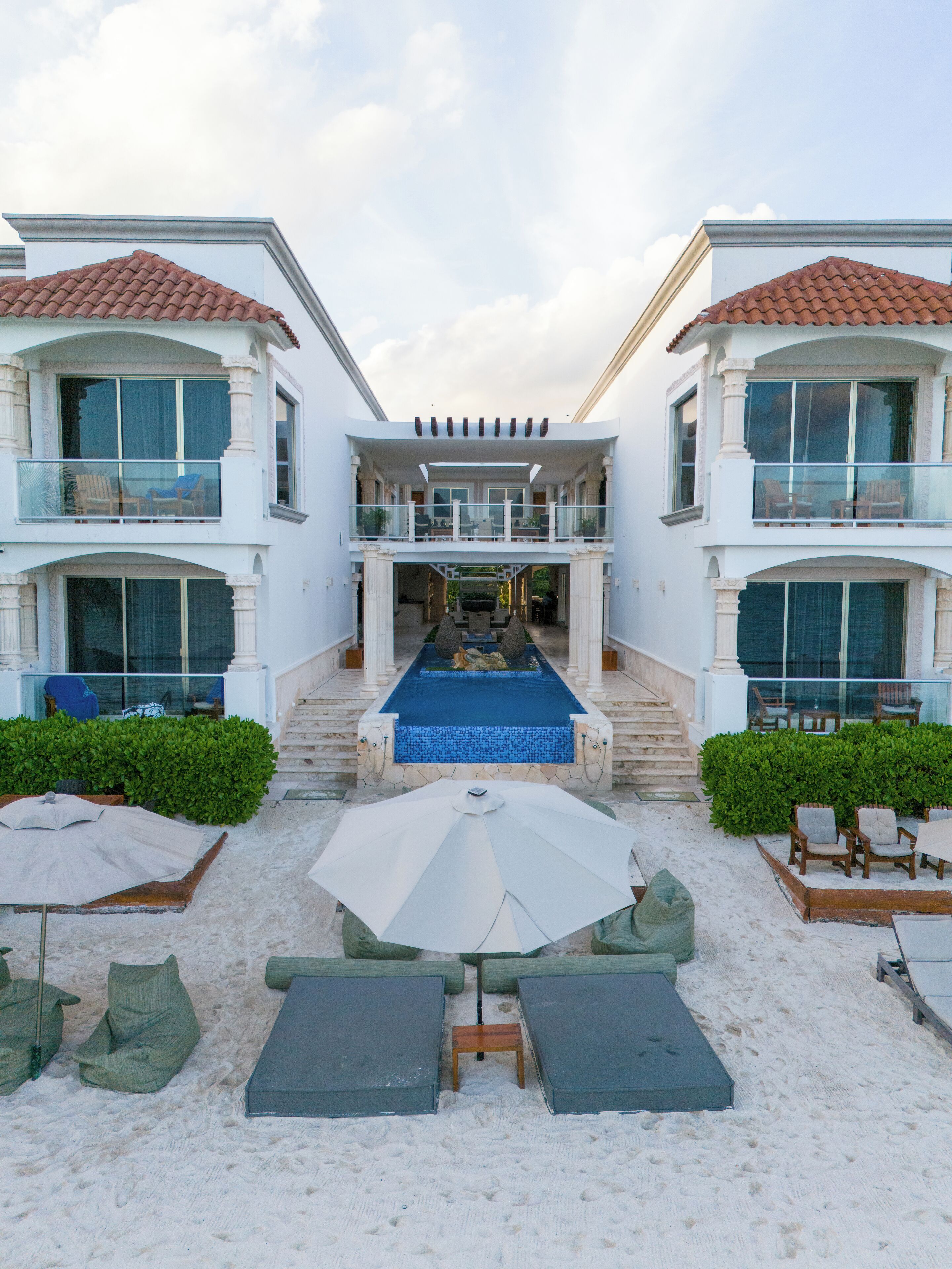 Un resort con piscina central, varios balcones y zonas de estar al aire libre.