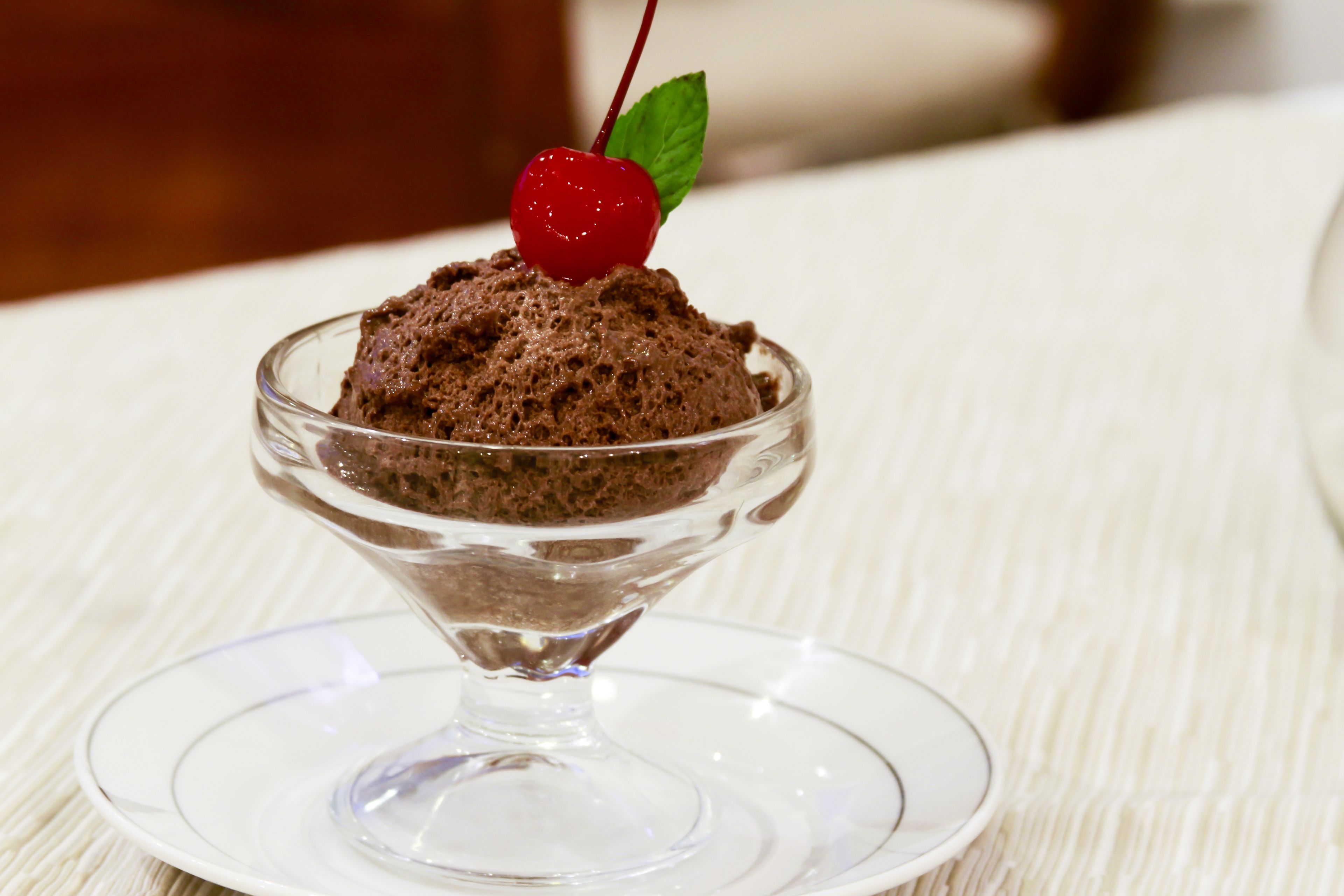Un postre en un bol de vidrio sobre un plato blanco.