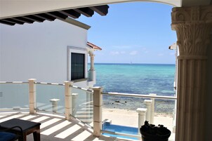 Un balcon offrant une vue dégagée sur l’océan et sur un voilier qui se trouve au loin.