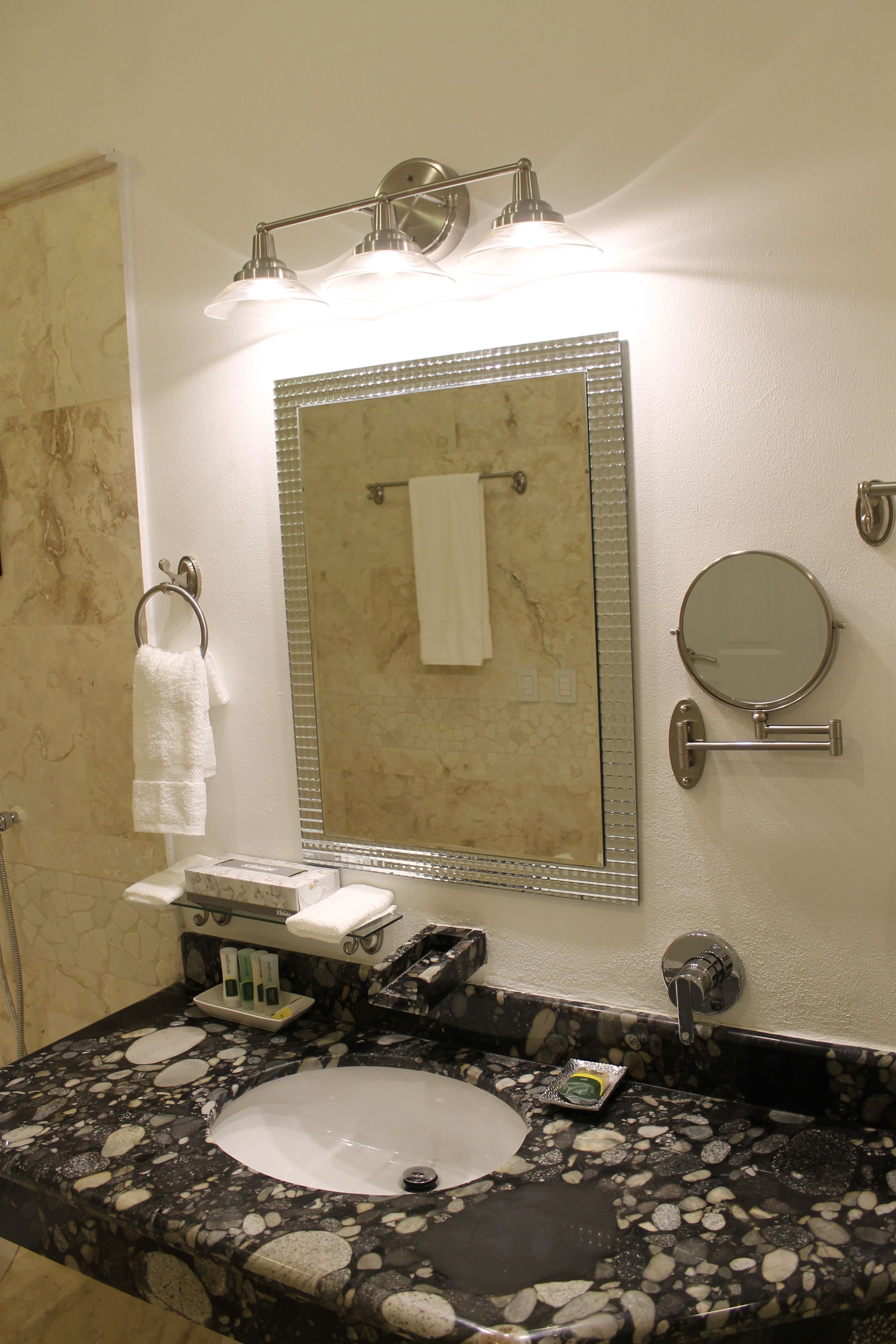 A bathroom with a marble sink, a large mirror, and a towel rack.