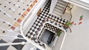 A checkered floor with a staircase, a small seating area, and a plant. - Hotel Málaga City Suites (Málaga)