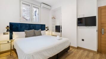 Un dormitorio moderno con una cama grande, un televisor montado en la pared y un armario.