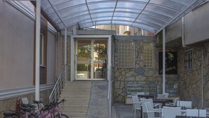 An outdoor patio area with a covered seating area, a staircase leading to an entrance, and bicycles parked to the side.