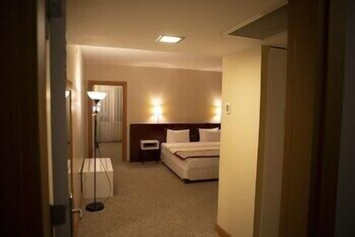 A hotel room with a bed, bedside table, lamp, and a nightstand.