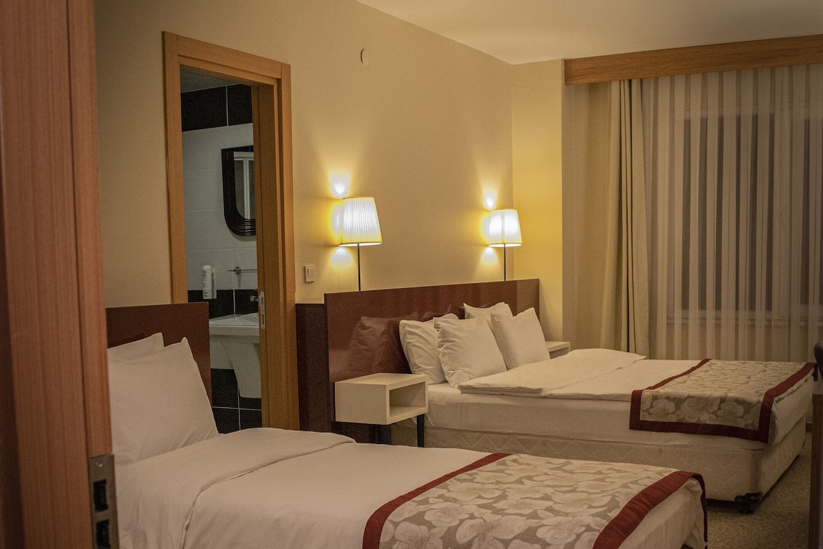 A hotel room with two beds, a bathroom, and a small desk.